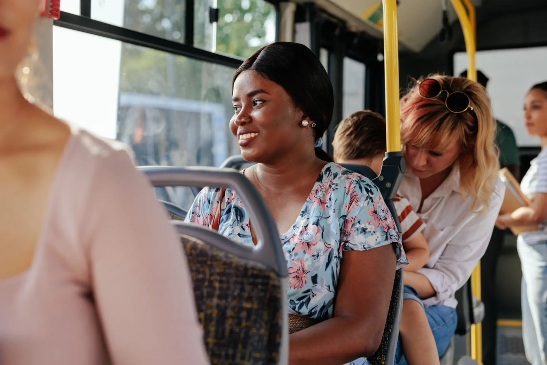 Person sitzt im Bus, schaut aus dem Fenster und lächelt.