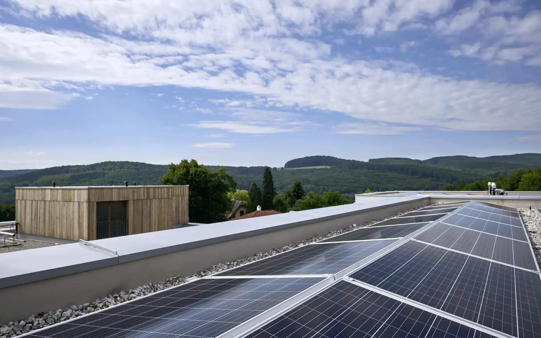 PV Anlage auf einem Dach dahinter ein Gebäude in Holzbauweise