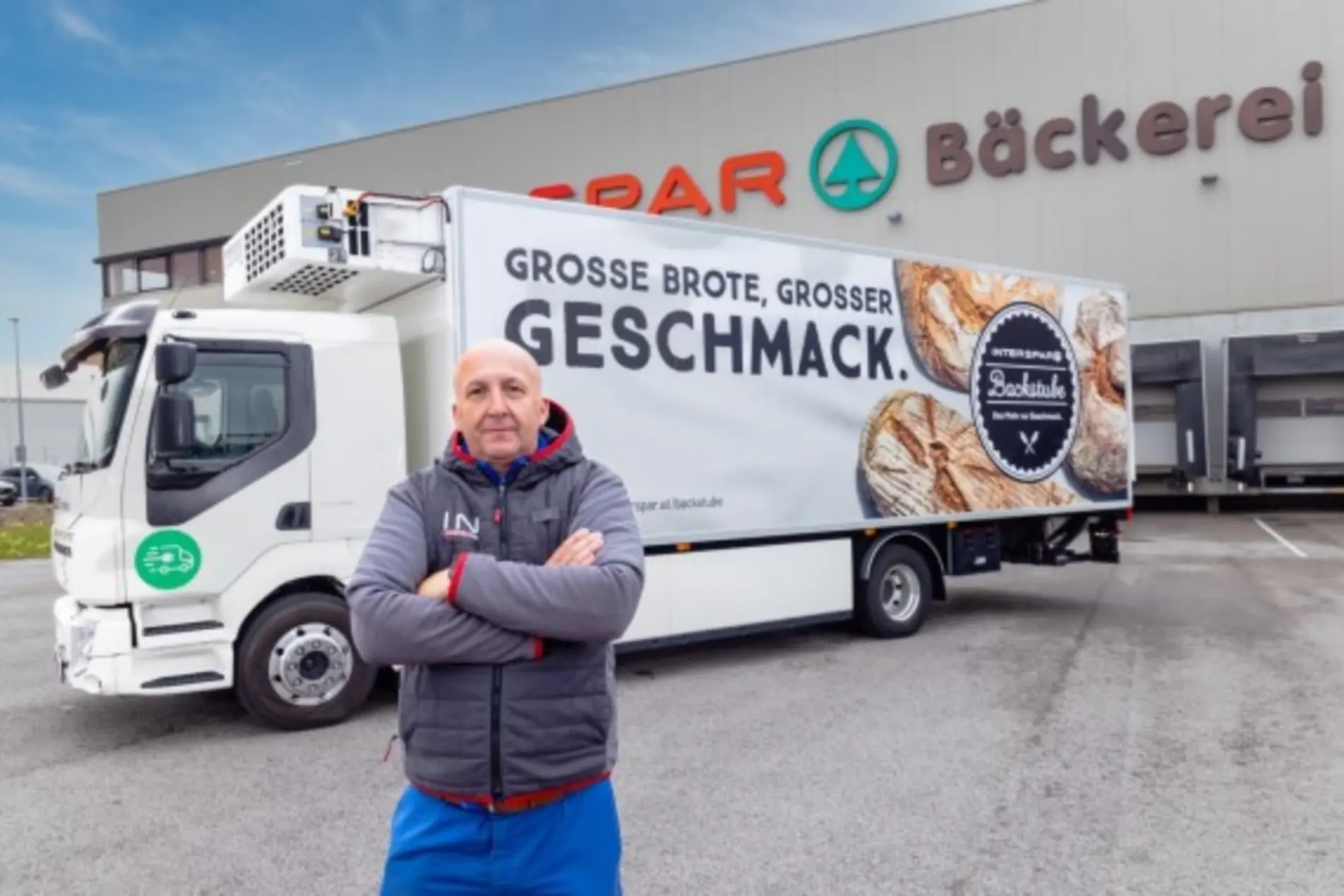 E-Lkw der INTERSPAR-Bäckerei in Kottingbrunn. Davor zu sehen ist ein Mann mit verschränkten Armen.